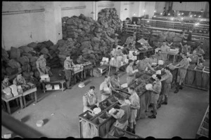 Chief NZ Post Office Cairo showing the checking of addresses and sorting of parcels for NZ Division, World War II - Photograph taken by George Bull