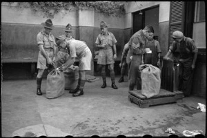 Sergeant D W Lake records the weight of consignment of NZEF Times to be transported to NZ troops - Photograph taken by George Bull