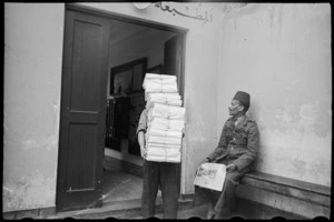 Porter carries bundles of the NZEF Times to truck for transportation, Egypt, World War II - Photograph taken by George Bull