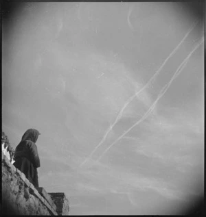 An Italian peasant woman watches the vapour trails from Allied aircraft over the Sangro River Front, World War II - Photograph taken by George Kaye
