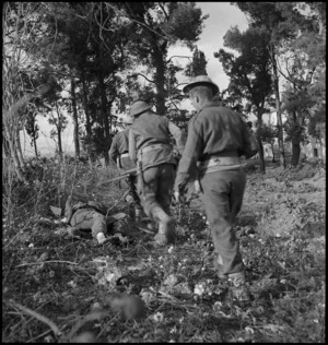 NZ soldiers pass dead German soldier during attack on German HQ at Castelfrentano, Italy, World War II - Photograph taken by George Kaye