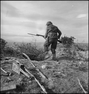 NZ infantry soldier rushes entrance of a German duggout during attack on German HQ near Castelfrentano, Italy, World War II - Photograph taken by George Kaye