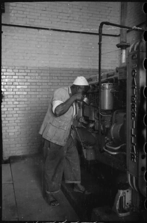 Local Egyptian attending to the diesel engine generating power for Maadi Camp, Egypt - Photograph taken by George Bull
