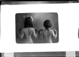Studio rectangle mask portrait of two unidentified young girls shirtless, back view with hands on shoulders, Christchurch