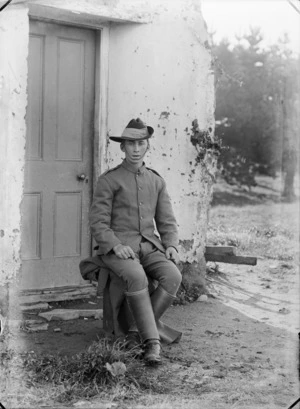 Portrait of unidentified World War I soldier with slouch hat, putties and stirrups sitting in front of a shepherd's hut [Mounted Rifles?], probably Christchurch region