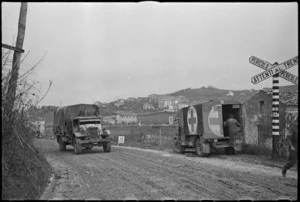 Vehicles of 2 NZ Divison near a railway crossing on road near Italian Front lines, World War II - Photograph taken by George Kaye