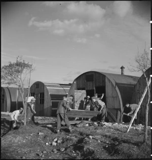 Italian workers assist New Zealanders in building Nissen huts at the NZ Advance Base Camp in Italy, World War II - Photograph taken by M D Elias