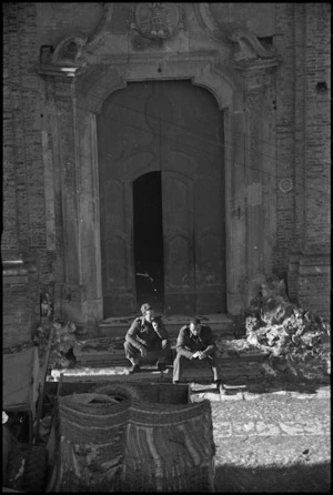 Two soldiers resting outside village church, Italy, World War II - Photograph taken by George Kaye