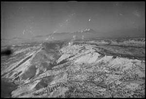 Aerial view of enemy held town of Orsogna with NZ Divisional Artillery shells seen bursting in the snow, Italy, World War II - Photograph taken by George Kaye