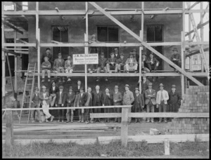 Group at a building site, by a sign advertising J W Alderton, building contractor
