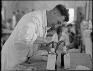 Removing tubes from bottles of donated blood and preliminary sealing at Maadi Camp Hospital, World War II - Photograph taken by G Bull