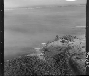 The Snow Rainger property on a headland with buildings, bush and steep cliffs at Hatfield's Beach settlement, North Auckland, with the Hibiscus Coastal Highway in the foreground