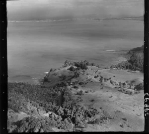 The Snow Rainger property on a headland with buildings, bush and steep cliffs at Hatfield's Beach settlement, North Auckland, with the Hibiscus Coastal Highway in the foreground