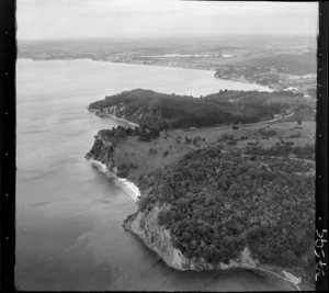 The Snow Rainger property on a headland with buildings, bush and steep cliffs, looking south to Hatfield's Beach settlement and Orewa, North Auckland, with the Hibiscus Coastal Highway and the Waiwera Hill Scenic Reserve