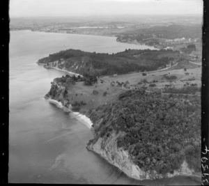 The Snow Rainger property on a headland with buildings, bush and steep cliffs, looking south to Hatfield's Beach settlement and Orewa, North Auckland, with the Hibiscus Coastal Highway and the Waiwera Hill Scenic Reserve