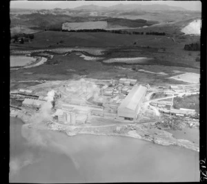 Aerial close-up view of the Portland Cement Works with railway on the inner Whangarei Harbour, with farmland beyond, Northland