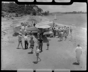 Tourist Air Travel, Grumman Widgeon aircraft ZK-BGQ at Paihia, Northland, includes crowd of people on beach