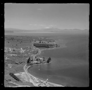 Lake Taupo shoreline with Lake Terrace road and Waipahihi Bay with buildings and jetties, with Mount Ruapehu beyond