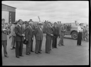 Mr D H Gendall, Mr J H Luxford Mayor of Auckland and Mr George Bolt on runway in front of TEAL Comet aircraft hangar with unidentified people, Whenuapai, Auckland Region