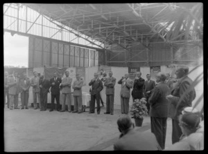 Luncheon in TEAL Comet aircraft hangar with unidentified dignitaries and crowd with BOAC signs, Whenuapai, Auckland