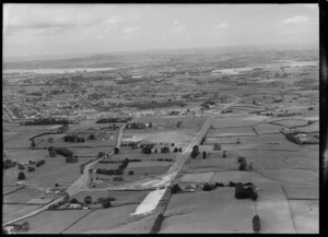 Construction of new Southern Highway next to Redoubt Road through farmland, Papatoetoe, with Auckland City beyond