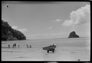 Waiwera, Rodney District, North Auckland, shows people on the beach, with a dinghy on a small trailor and Mahurangi Island in the background