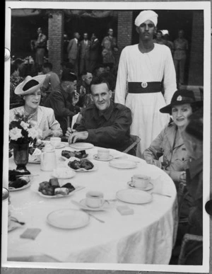 Lady Freyberg and Mrs Casey listening to the experiences of a New Zealander at a garden party for repatriated POWs, Gazira Sporting Club, Cairo