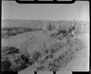 The Clutha River with tree lined banks and buildings, hills beyond, Roxburgh, Otago Region