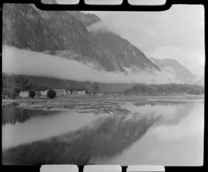 Milford Sound buildings with low cloud and steep bush covered mountains beyond, Fiordland National Park, Southland Region