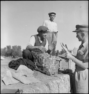 Lieutenant R H Pope bargains with a local fruit vendor for grapes, Italy