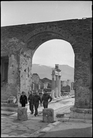 New Zealand soldiers with a guide walk beneath archway in the Via Fortuna, Pompei, Italy, World War II - Photograph taken by George Kaye