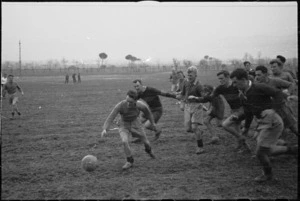 Members of NZ Public Relations Service play rugby football in the rain and mud behind the lines, Italian Front, World War II - Photograph taken by George Kaye