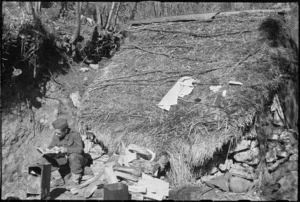D Hedgewick reads in the sun outside a stone-walled and thatch structure on the 5th Army Front in Italy, World War II - Photograph taken by George Kaye