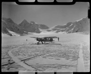 Mount Cook Air Services Auster ZK-BLZ Ski Plane and two unidentified people at the head of the Tasman Glacier with snow covered mountains beyond, Mount Cook National Park, Canterbury Region