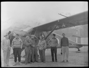 Sir Edmund Hillary and six men in front of Antarctic Beaver NZ6001 Ski Plane, Mount Cook Airfield, Mount Cook National Park, Canterbury Region