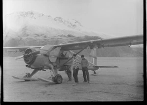 Sir Edmund Hillary and Sergeant W Tarr inspecting the Antarctic Beaver NZ6001 Ski Plane, Mount Cook Airfield, Mount Cook National Park, Canterbury Region