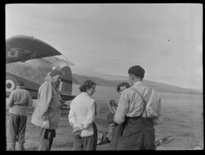 Unidentified men and women [including Louise Hillary?] beside a Mount Cook Air Services Ltd, Auster aircraft NZ-1707, Mount Cook Airfield, Mount Cook National Park, Canterbury Region, during the preparation for the Antarctic Expedition
