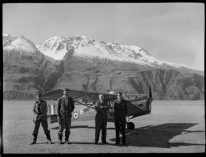 Four unidentified men, in front of a Mount Cook Air Services Ltd, Auster aircraft NZ-1707, Mount Cook Airfield, Mount Cook National Park, Canterbury Region, during the preparation for the Antarctic Expedition