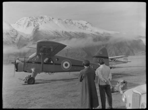 Two unidentified women watch as a Mount Cook Air Services Ltd aircraft NZ-6001 takes off from Mount Cook Airfield, Mount Cook National Park, Canterbury Region, during the preparation for the Antarctic Expedition
