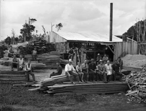 Timber workers sitting on planks of wood at a timber mill