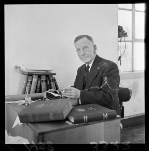 Evening Post shipping reporter Sydney David Waters smoking a cigarette at his typewriter