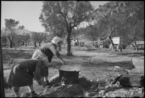 Italian peasant women cook on open fires while transport passes on 5th Army Front, southern Italy, World War II - Photograph taken by George Kaye