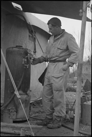 D McErlick attends boiler supplying hot water to showers at the Cassino Front, Italy, World War II - Photograph taken by George Kaye