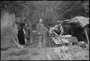 Italian civilian families outside cave in which they now live after German demolition of their homes, Italy, World War II - Photograph taken by George Kaye
