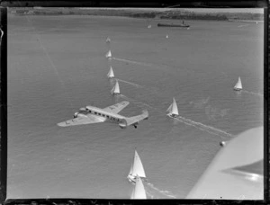 Lockheed Model 10 Electra monoplane ZK-AFD, flying over sailing boats in an unidentified harbour