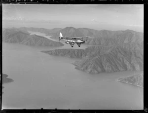 'Karoro', a de Havilland DH 86 aeroplane, in flight over unidentified landscape