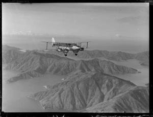 'Karoro', a de Havilland DH 86 aeroplane, in flight over unidentified landscape