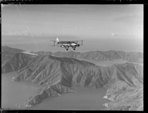 'Karoro', a de Havilland DH 86 aeroplane, in flight over unidentified landscape