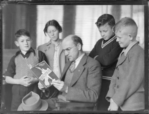 Portrait of G Smith reading Wingspread book with three young boys and a teenaged girl (Betta Models?)