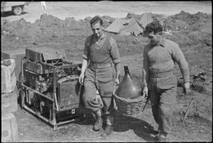 P D Bouzaid and C L Jackson carrying a large jar of battery acid on the Cassino Front in Italy, World War II - Photograph taken by George Kaye